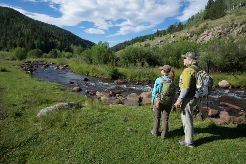 A man and woman hike next to a babbling mountain brook