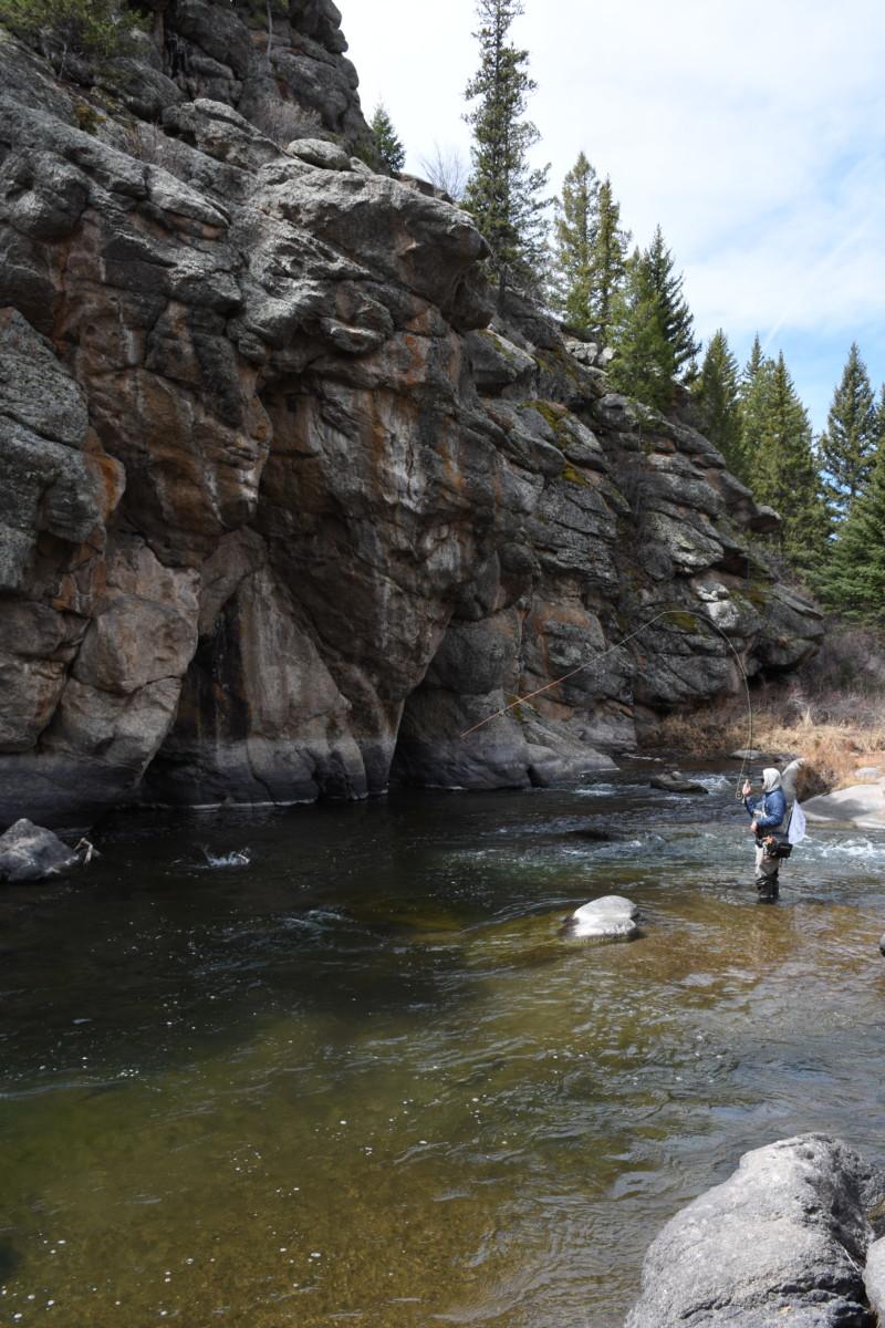 Angler fly fishing near rock wall